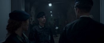 Movie still from “Black Crab” (2022), directed by Adam Berg – A man in a uniform is standing in a dark tunnel; Medium shot, Over the shoulder angle