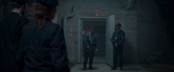 Movie still from “Black Crab” (2022), directed by Adam Berg – A group of men standing next to each other in front of a building; Wide shot, Low angle