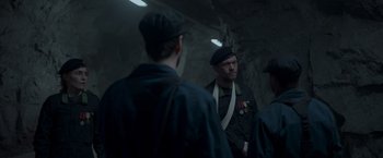 Movie still from “Black Crab” (2022), directed by Adam Berg – A group of men standing next to each other in a tunnel; Medium shot, Over the shoulder angle