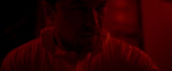 Movie still from “Black Crab” (2022), directed by Adam Berg – A person in a dark room; Close Up shot, Over the shoulder angle