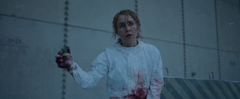 Movie still from “Black Crab” (2022), directed by Adam Berg – A woman in a white lab coat with blood on her hands; Medium shot, Over the shoulder angle