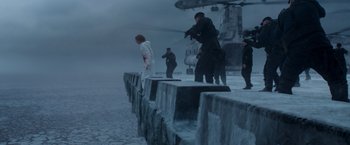 Movie still from “Black Crab” (2022), directed by Adam Berg – A group of people standing on top of a rock wall; Extreme Wide shot, Low angle
