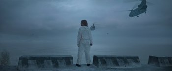Movie still from “Black Crab” (2022), directed by Adam Berg – A man standing on a pier looking out at a helicopter; Extreme Wide shot, Low angle