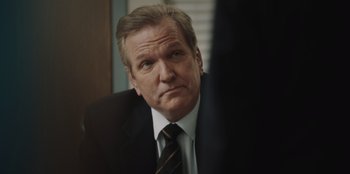 Movie still from “BlackBerry” (2023), directed by Matt Johnson – A man in a suit and a tie; Close Up shot, Over the shoulder angle