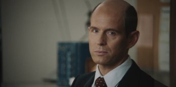 Movie still from “BlackBerry” (2023), directed by Matt Johnson – A man in a suit and tie looking at the camera; Close Up shot, Over the shoulder angle