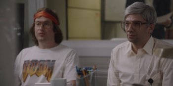 Movie still from “BlackBerry” (2023), directed by Matt Johnson – Two people sitting at a table in front of a cup; Medium shot, Over the shoulder angle