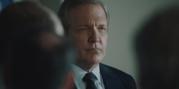 Movie still from “BlackBerry” (2023), directed by Matt Johnson – An older man in a suit and tie looking to his left; Close Up shot, Over the shoulder angle