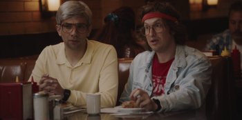 Movie still from “BlackBerry” (2023), directed by Matt Johnson – Two people sitting at a table with a plate of food; Close Up shot, Over the shoulder angle