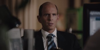Movie still from “BlackBerry” (2023), directed by Matt Johnson – A man in a suit and tie looking at the camera; Close Up shot, Over the shoulder angle