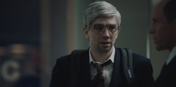 Movie still from “BlackBerry” (2023), directed by Matt Johnson – A man in a suit and tie wearing glasses; Close Up shot, Over the shoulder angle