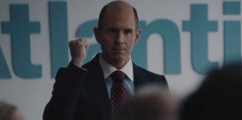 Movie still from “BlackBerry” (2023), directed by Matt Johnson – A man in a suit and tie raising his fist in the air; Close Up shot, Over the shoulder angle