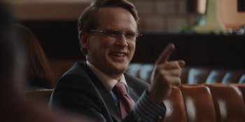 Movie still from “BlackBerry” (2023), directed by Matt Johnson – A man in a suit and tie pointing to the side; Close Up shot, Over the shoulder angle