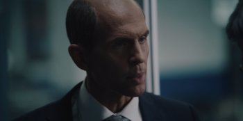 Movie still from “BlackBerry” (2023), directed by Matt Johnson – A man in a suit and tie looking to his left; Close Up shot, Over the shoulder angle