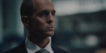 Movie still from “BlackBerry” (2023), directed by Matt Johnson – A person wearing a suit and tie; Close Up shot, Over the shoulder angle