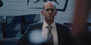 Movie still from “BlackBerry” (2023), directed by Matt Johnson – A man wearing a suit and tie in front of a wall; Close Up shot, Low angle