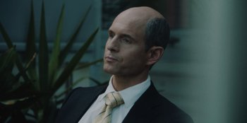 Movie still from “BlackBerry” (2023), directed by Matt Johnson – A man in a suit and tie looking to his left; Close Up shot, Over the shoulder angle