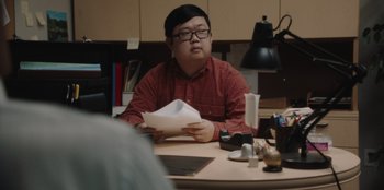 Movie still from “BlackBerry” (2023), directed by Matt Johnson – A man sitting at a table with papers in his hands; Medium shot, Over the shoulder angle