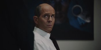 Movie still from “BlackBerry” (2023), directed by Matt Johnson – A bald man in a white shirt and black tie; Close Up shot, Over the shoulder angle
