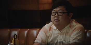 Movie still from “BlackBerry” (2023), directed by Matt Johnson – A man sitting on top of a brown leather couch; Close Up shot, Over the shoulder angle