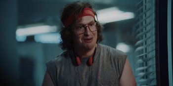 Movie still from “BlackBerry” (2023), directed by Matt Johnson – A man with glasses and a red head band; Close Up shot, Over the shoulder angle