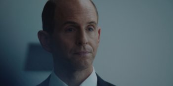 Movie still from “BlackBerry” (2023), directed by Matt Johnson – A person wearing a suit and tie; Close Up shot, Over the shoulder angle