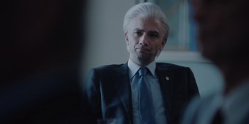 Movie still from “BlackBerry” (2023), directed by Matt Johnson – A man in a suit and tie looking at the camera; Close Up shot, Over the shoulder angle