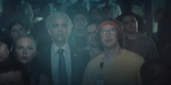 Movie still from “BlackBerry” (2023), directed by Matt Johnson – A group of people standing in front of a microphone; Medium shot, Low angle