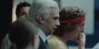 Movie still from “BlackBerry” (2023), directed by Matt Johnson – A man in a suit and tie next to a woman in a yellow dress; Close Up shot, Over the shoulder angle