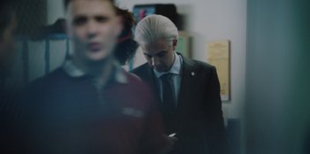 Movie still from “BlackBerry” (2023), directed by Matt Johnson – A man in a black suit and a woman in a black suit; Medium shot, Over the shoulder angle