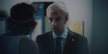 Movie still from “BlackBerry” (2023), directed by Matt Johnson – A man in a suit and tie talking to a woman; Close Up shot, Over the shoulder angle