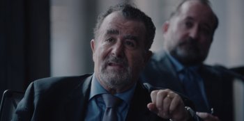 Movie still from “BlackBerry” (2023), directed by Matt Johnson – An older man wearing a suit and tie; Close Up shot, Over the shoulder angle