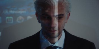 Movie still from “BlackBerry” (2023), directed by Matt Johnson – A person wearing a suit and tie; Close Up shot, High angle