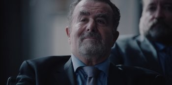 Movie still from “BlackBerry” (2023), directed by Matt Johnson – An older man wearing a suit and tie; Close Up shot, Over the shoulder angle