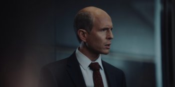 Movie still from “BlackBerry” (2023), directed by Matt Johnson – A man in a suit and red tie looking to his left; Close Up shot, Over the shoulder angle
