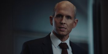Movie still from “BlackBerry” (2023), directed by Matt Johnson – A man in a suit and tie looking at the camera; Close Up shot, Over the shoulder angle