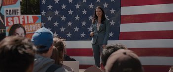 Movie still from “Blacklight” (2022), directed by Mark Williams – A woman standing in front of an american flag; Wide shot, Low angle