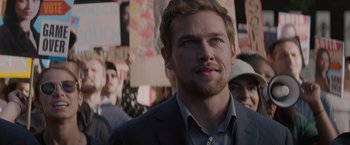 Movie still from “Blacklight” (2022), directed by Mark Williams – A person wearing a suit and tie; Close Up shot, Over the shoulder angle