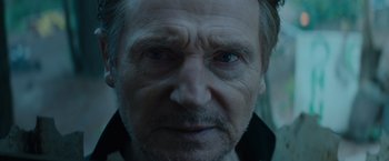 Movie still from “Blacklight” (2022), directed by Mark Williams – A man's face in a dark room; Close Up shot, Low angle