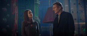 Movie still from “Blacklight” (2022), directed by Mark Williams – A man and a woman standing next to each other in a room; Medium shot, Low angle