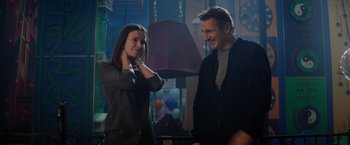 Movie still from “Blacklight” (2022), directed by Mark Williams – A man and a woman standing next to each other in a room; Medium shot, Over the shoulder angle