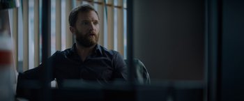 Movie still from “Blacklight” (2022), directed by Mark Williams – A man sitting in front of a computer monitor; Medium shot, Over the shoulder angle