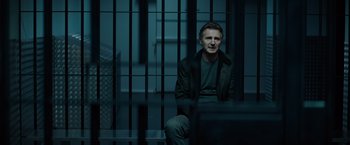 Movie still from “Blacklight” (2022), directed by Mark Williams – A man sitting on a bench in a jail cell; Medium shot, Low angle