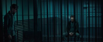 Movie still from “Blacklight” (2022), directed by Mark Williams – A man sitting in a jail cell at night; Wide shot, Low angle
