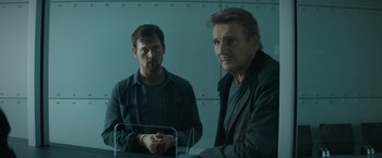 Movie still from “Blacklight” (2022), directed by Mark Williams – Two men standing next to each other in front of a wall; Medium shot, Over the shoulder angle