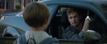 Movie still from “Blacklight” (2022), directed by Mark Williams – A man sitting in the passenger seat of a car looking at a boy; Close Up shot, Over the shoulder angle