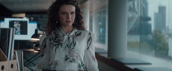 Movie still from “Blacklight” (2022), directed by Mark Williams – A woman in a white shirt and a floral blouse; Medium shot, Low angle