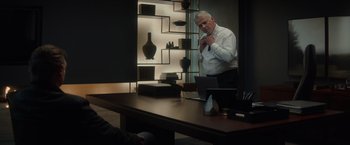 Movie still from “Blacklight” (2022), directed by Mark Williams – An older man standing in front of a table; Medium shot, Over the shoulder angle