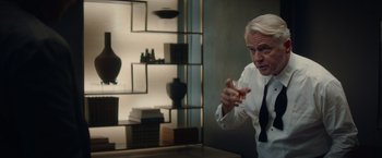 Movie still from “Blacklight” (2022), directed by Mark Williams – An older man holding a wine glass in his hand; Medium shot, Over the shoulder angle