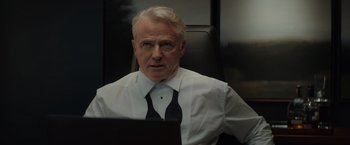 Movie still from “Blacklight” (2022), directed by Mark Williams – An older man wearing a white dress shirt and a black tie; Close Up shot, Over the shoulder angle
