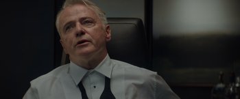 Movie still from “Blacklight” (2022), directed by Mark Williams – An older man wearing a white shirt and black tie; Close Up shot, Low angle